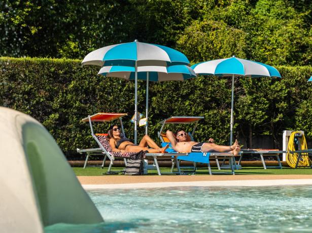 People relax on sun loungers by the pool.