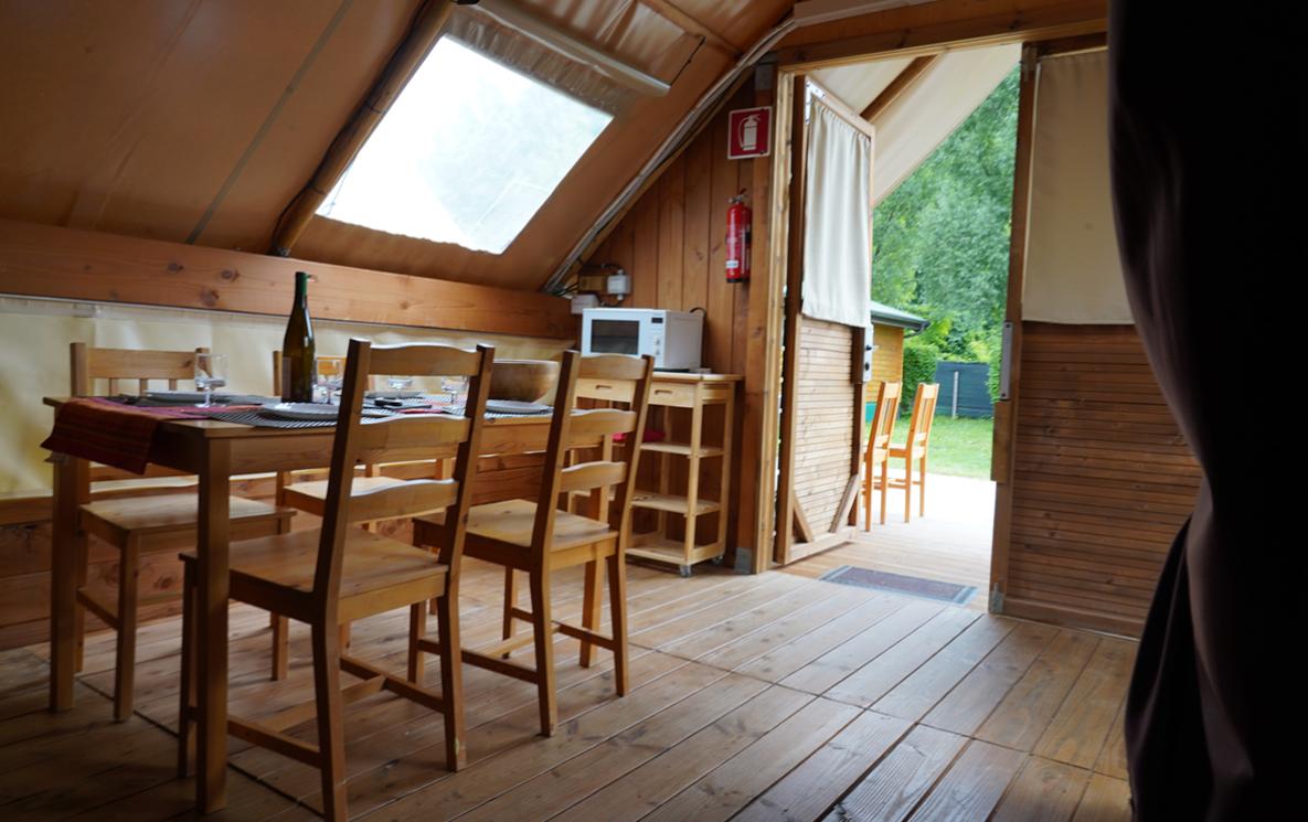 Innenraum eines Glamping-Zeltes mit Holztisch und Stühlen.