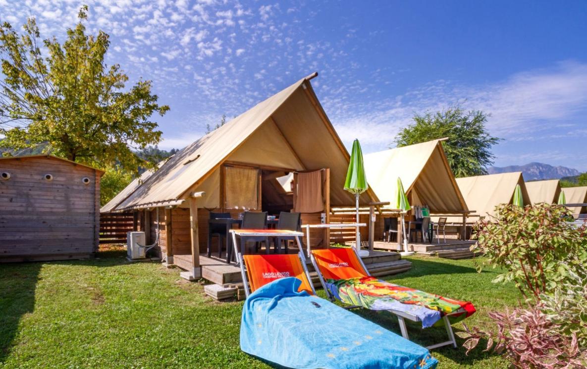 Glamping-Zelte mit Liegen und Sonnenschirmen in natürlicher Umgebung.