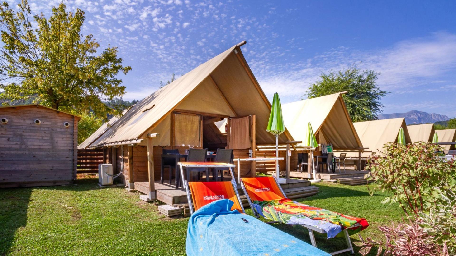 Glamping-Zelte auf einem Campingplatz mit Liegestühlen.