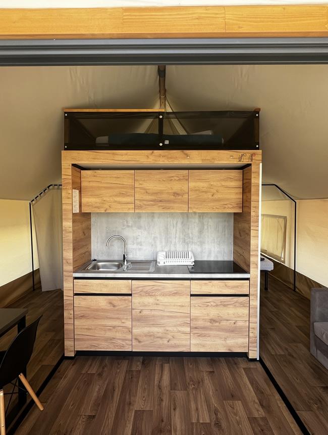 Compact wooden kitchen with sink and cabinets.